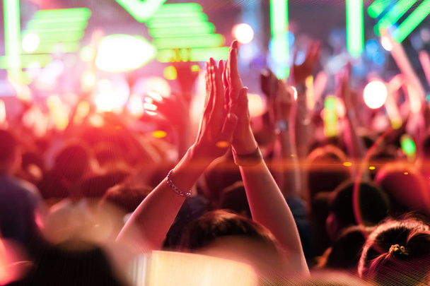 Menigte van mensen handen klappen Concert podium verlichting, kleur van het jaar 2019. - Foto, afbeelding