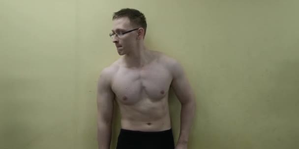 Sportos férfi pózol a falnak az edzőteremben - Felvétel, videó