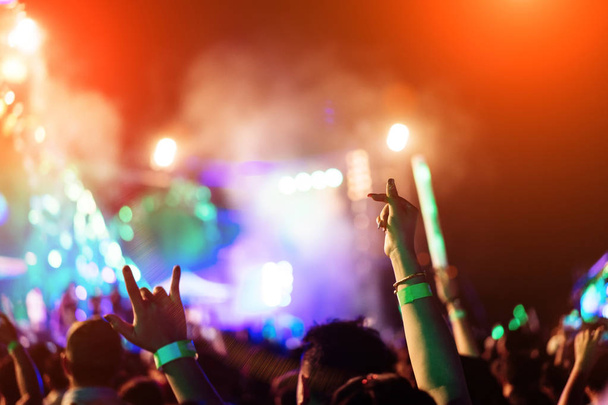 Multidão de mãos para cima amantes concerto palco luzes e pessoas fã público silhueta levantando as mãos no festival de música vista traseira com holofotes efeito brilhante
 - Foto, Imagem