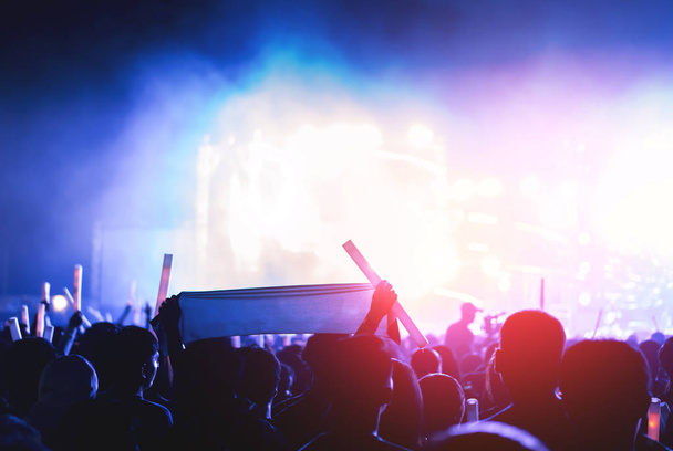 Siluetti yleisö konsertti vaiheessa valot ja ihmiset tuuletin yleisö nostaa kädet tai hehku tikku tilalla musiikkifestivaalin takana
  - Valokuva, kuva