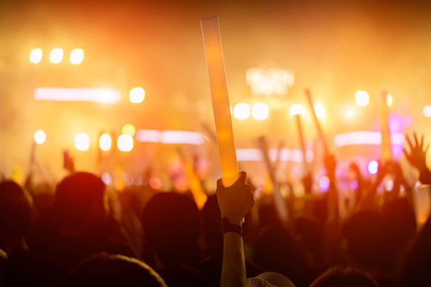 Multidão de luzes de palco de concerto e pessoas silhueta de público fã levantando as mãos ou brilho vara segurando na vista traseira do festival de música com holofotes efeito brilhante e fumaça
 - Foto, Imagem