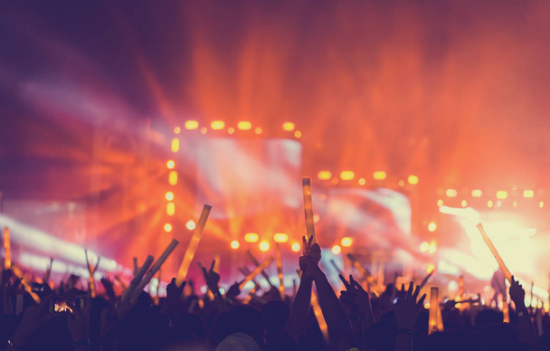 Sziluettjét tömeg koncert szakaszban fények és emberek rajongó közönség emeli a kezét, vagy világító rúd tartja a zene fesztivál hátsó nézet  - Fotó, kép