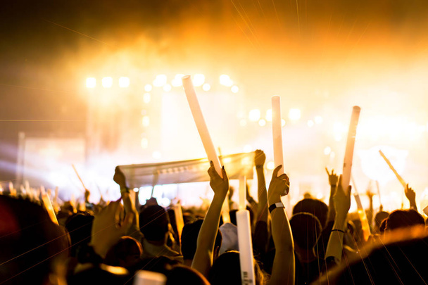 Dav koncert fázi světla a lidé ventilátor publikum silueta rukou nebo palicí drží v hudebním festivalu zadní pohled s zářící efekt bodového reflektoru a kouř - Fotografie, Obrázek