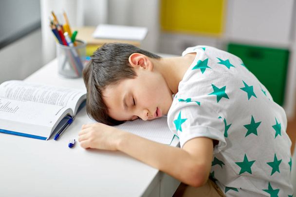 tired student boy sleeping on table at home - Foto, afbeelding