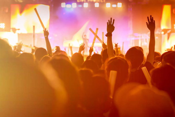 Multitud de luces de escenario de concierto y la gente fan silueta de la audiencia levantando las manos o palo de brillo celebración en la vista trasera del festival de música con reflector efecto brillante y humo
 - Foto, Imagen
