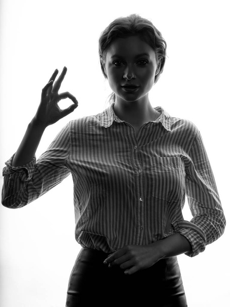 Retrato de mujer rizada joven con camisa a rayas que muestra signo OK sobre fondo blanco
 - Foto, imagen