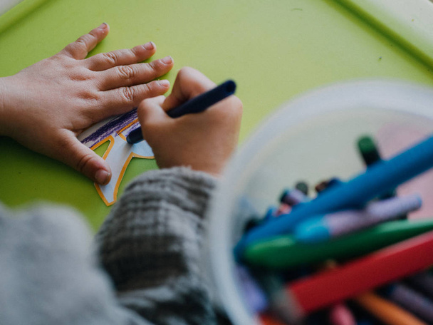 Pintura de niña de tres años con colores en mesa verde
 - Foto, Imagen