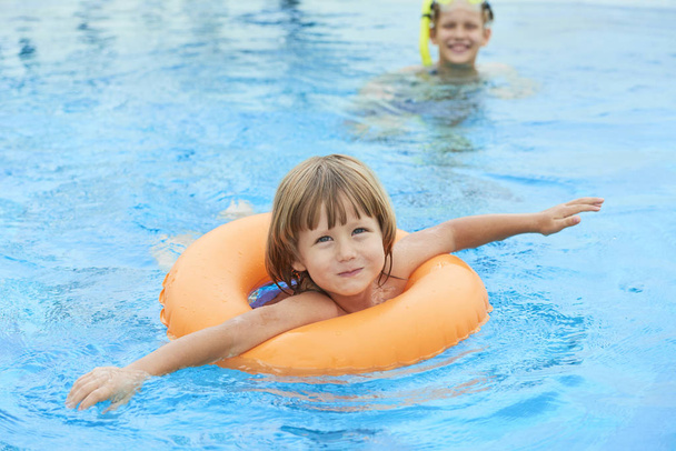 Ładny, mały chłopiec, pływanie w basenie z nadmuchiwanym pierścieniem na letnie wakacje - Zdjęcie, obraz