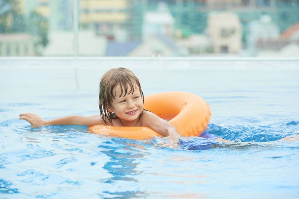 Joyeux petit enfant nageant dans l'anneau gonflable dans la piscine
 - Photo, image