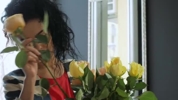 Beautiful curly woman forms a bouquet by the window - Imágenes, Vídeo