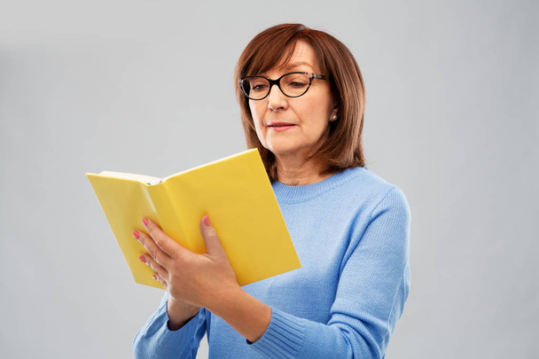 senior woman in glasses reading book - Фото, зображення