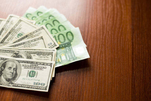Δολάρια ΗΠΑ και ευρώ τραπεζογραμμάτια υφή. σκούρο ξύλο φόντο των εκατό δολαρίων και ευρώ λογαριασμών. - Φωτογραφία, εικόνα