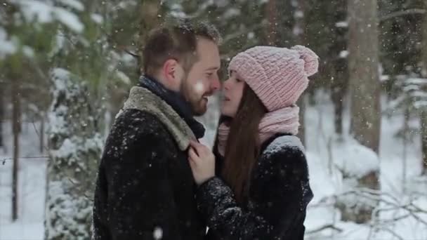 Casal caucasiano bonito jovem que se beija abaixo de uma neve em uma floresta de inverno. Millennials na moda se divertindo toghether. Imagens sinceras de um jovem casal na floresta. Movimento lento
. - Filmagem, Vídeo