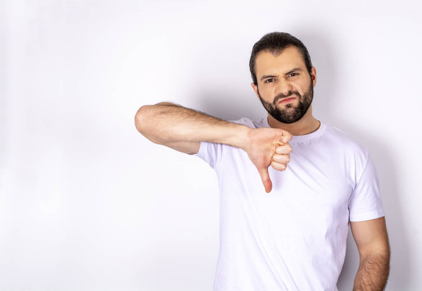 handsome man in white t-shirt over white background showing dislike - Photo, Image