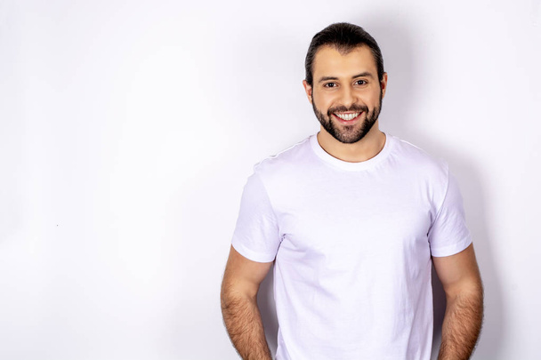 Handsome man in white t-shirt over white background smiling - Foto, afbeelding