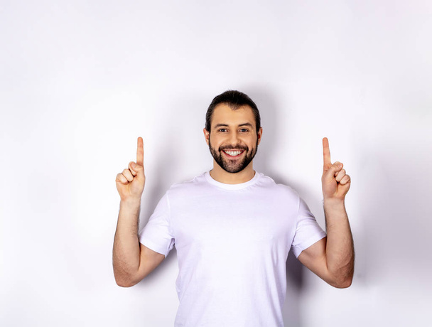 handsome man in white t-shirt on white background, shows up - Fotó, kép