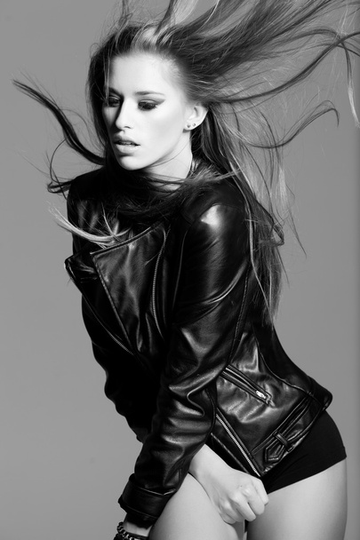 fiatal modell visel egy bőr kabát divat a stúdióban pózol - Fotó, kép