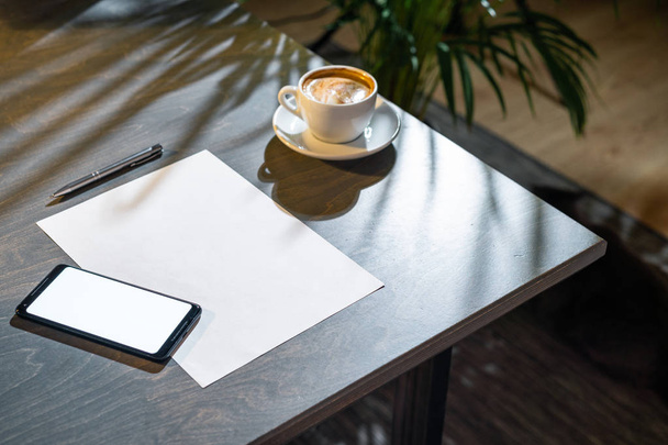 Primo piano di tazza di caffè, bicchieri, carta, penna e telefono cellulare con schermo bianco
. - Foto, immagini