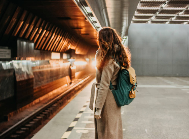 Jonge vrouw krullend rood hoofd meisje reiziger met rugzak en kaart in metrostation - Foto, afbeelding