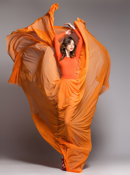 stüdyoda dinamik poz uzun Turuncu elbiseli güzel kadın - Fotoğraf, Görsel