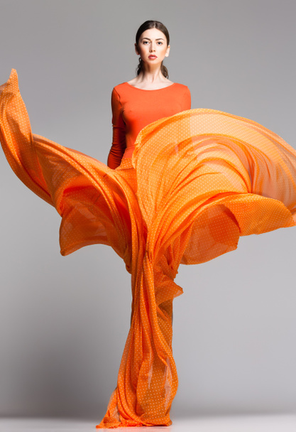hermosa mujer en vestido largo naranja posando dinámico en el estudio
 - Foto, imagen