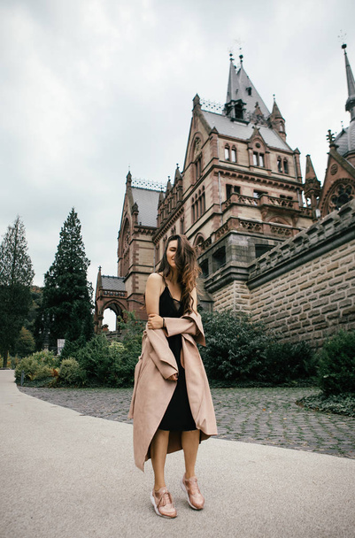 Sexy girl in black dress and pastel pink coat  posing at the medieval castle - Foto, immagini
