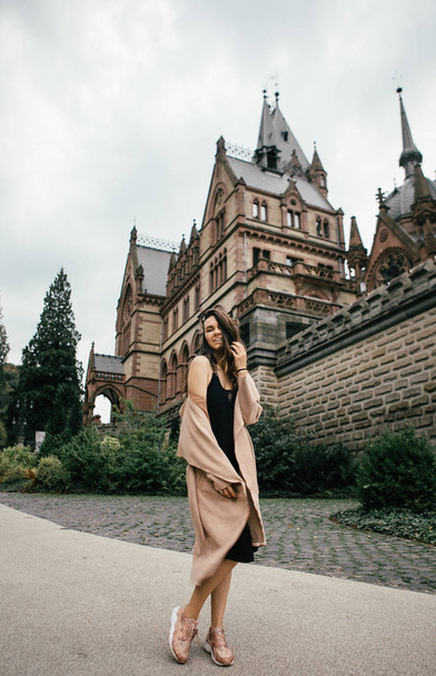 Sexy girl in black dress, pastel pink coat and hat posing at the medieval castle - Zdjęcie, obraz