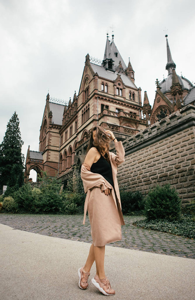 Sexy girl in black dress, pastel pink coat and hat posing at the medieval castle - Foto, immagini