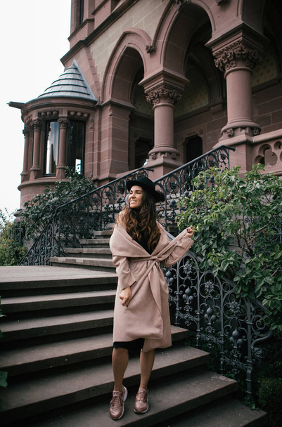 Sexy girl in black dress, pastel pink coat and hat posing at the medieval castle - 写真・画像