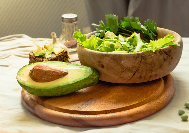 Fresh delicious green salad with avocado in a wooden plate and g - Foto, Imagen
