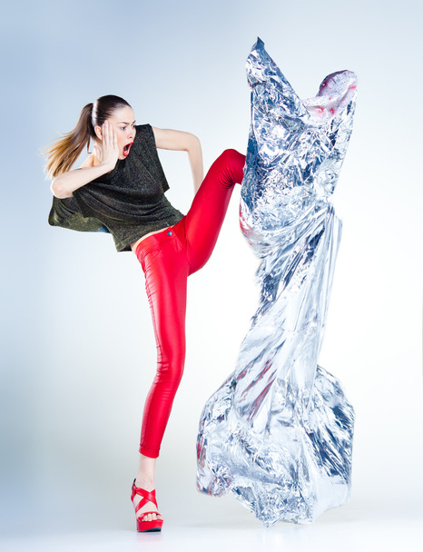 σέξι μοντέλο με λεπτό σώμα ντυμένος με κόκκινο άλμα στο στούντιο blueish φόντο - Φωτογραφία, εικόνα