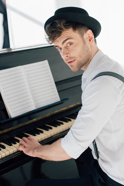 красивый пианист в стильной одежде играет на пианино дома
 - Фото, изображение
