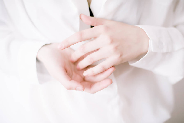 Крупним планом зображення красивих жіночих рук з легким манікюром на нігтях. Крем для рук, манікюр та засоби для догляду за красою. Елегантні і витончені руки з тонкими витонченими пальцями. - Зображення
 - Фото, зображення