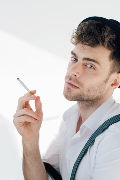 handsome man holding cigarette and looking at camera  - Фото, зображення
