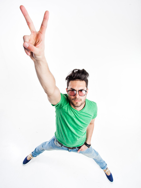 funny handsome man with hipster glasses showing victory and smiling - wide angle shot - Foto, Imagem