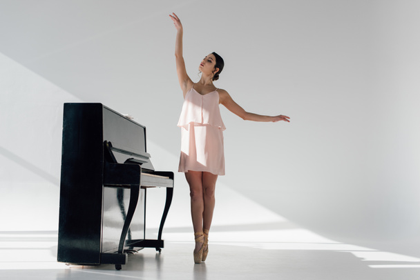 graceful ballerina dancing near black piano  - Foto, imagen