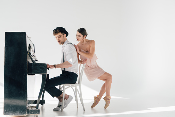 attractive ballerina touching handsome musician playing piano  - Foto, Imagem