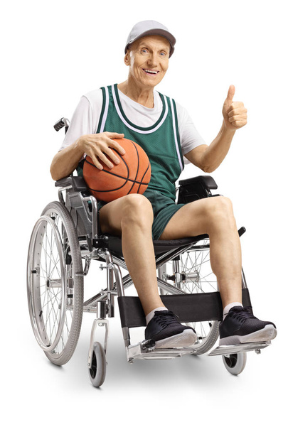 Disabled elderly man in a wheelchair holding a basketball and showing thumbs up isolated on white background - Zdjęcie, obraz