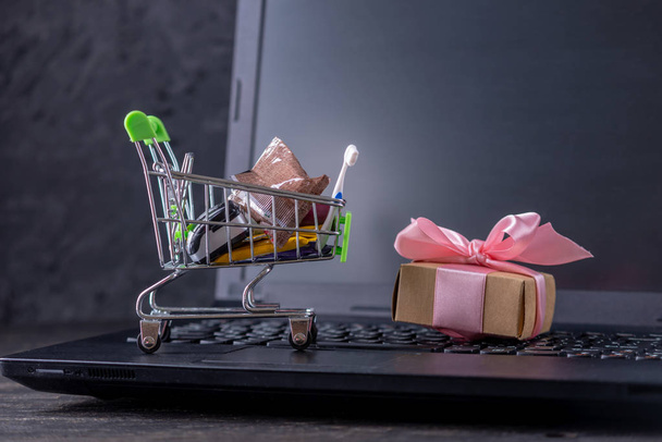 Acquisti giornalieri e regali nel carrello della spesa sulla tastiera del computer portatile. Shopping nei negozi online
 - Foto, immagini