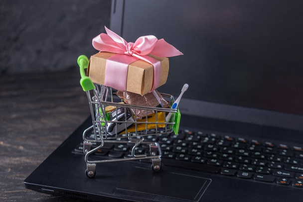 Codzienne zakupy i prezenty w koszyku na klawiaturze laptopa. Zakupy w sklepach internetowych - Zdjęcie, obraz