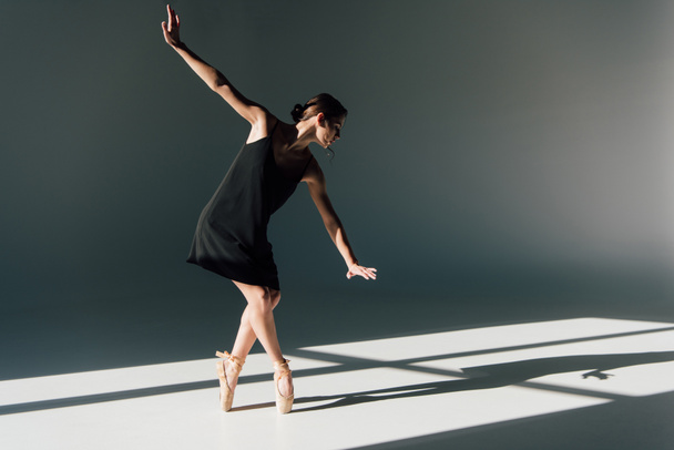 витончена молода балерина в чорній сукні танцює на сонячному світлі
  - Фото, зображення
