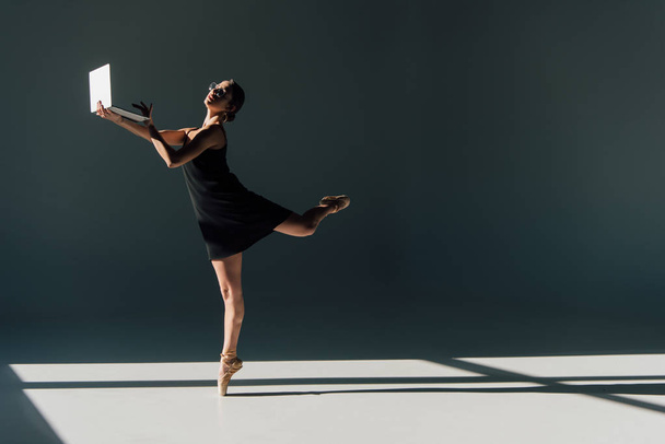 bailarina joven en vestido negro y anteojos bailando con laptop
 - Foto, imagen