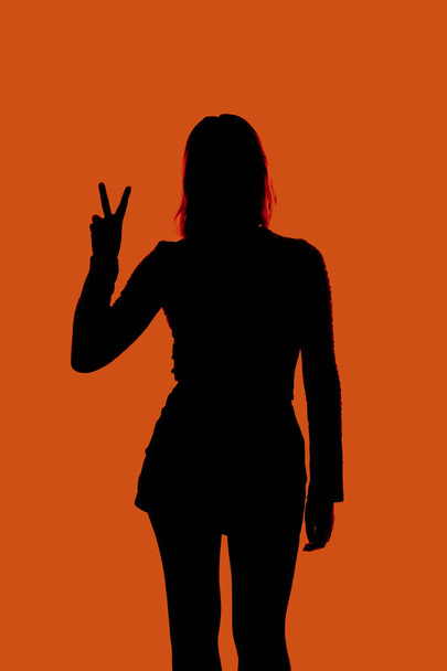 Girl making the sign of victory on a plain background - Foto, Imagen