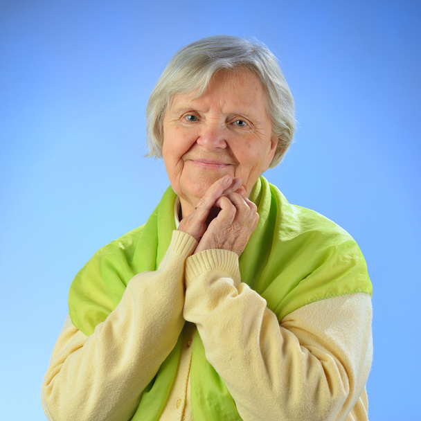 Senior happy woman with grey hairs against blue background. - Zdjęcie, obraz