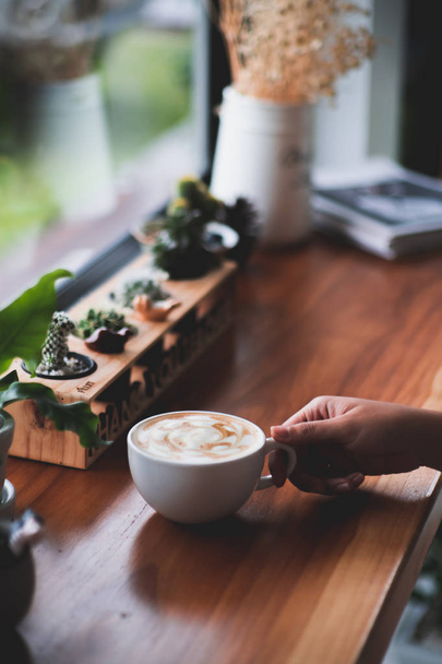 white hot coffee cup on wood table.woman hand holding coffee cup. - Фото, зображення