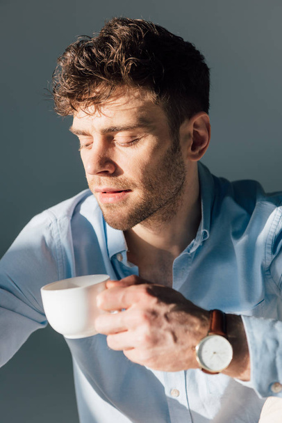 szép töprengő ember, aki kávéscsésze ülve napfény  - Fotó, kép