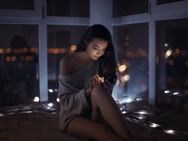 Woman use of mobile phone indoors at night - Foto, Imagen