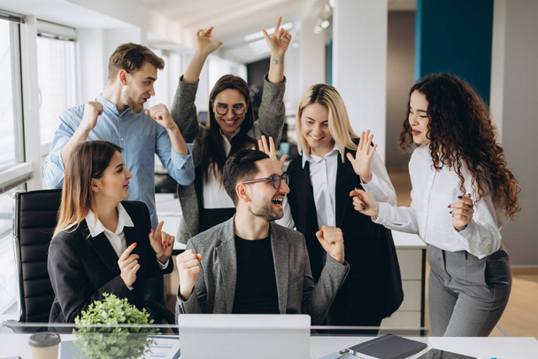 Férfi dolgozó osztozik jó hír a többnemzetiségű kollégákkal, a megosztott munkaterület, változatos alkalmazottak üvölteni a boldogság vállalati siker, vagy a cél eléréséhez, izgatott csapatot ünneplése - Fotó, kép