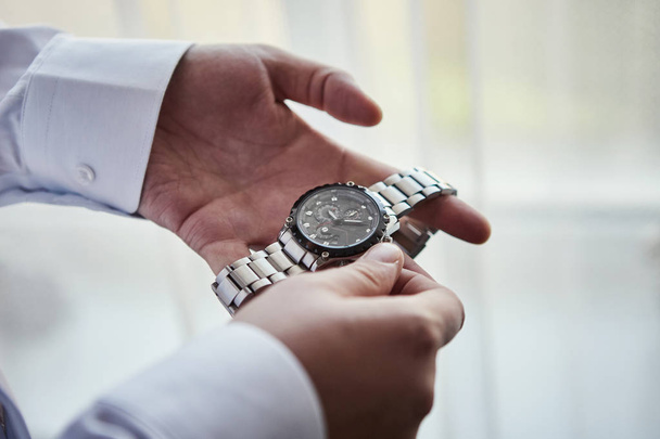 homme d'affaires vérifiant l'heure sur sa montre-bracelet, homme mettant horloge sur la main, marié se préparer le matin avant la cérémonie de mariage. Hommes Mode - Photo, image