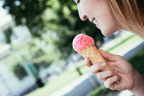 Smiling girl enjoys her strawberry ice cream during a summer day - 写真・画像